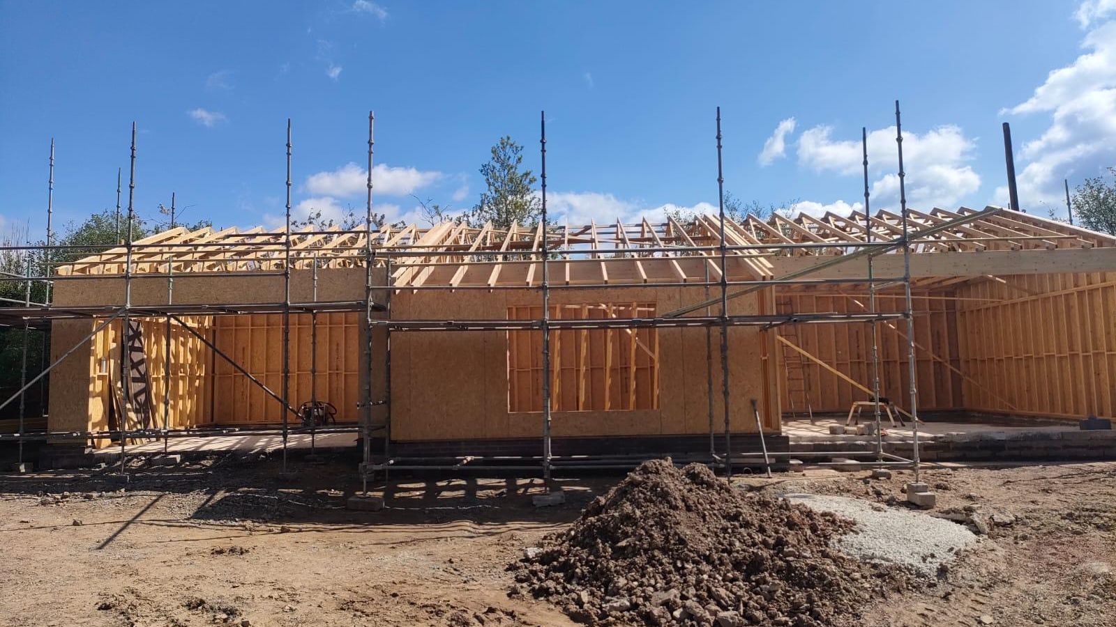 A timber frame extension under construction, with the wall panels and roof trusses erected by Etopia Custom